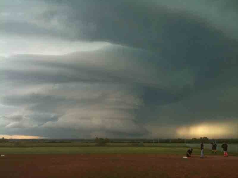 A slow-moving thunderstorm builds west of Bowden as slo-pitch players get set for their game on July 7. The storm cell spawned a tornado near Innisfail later that evening.