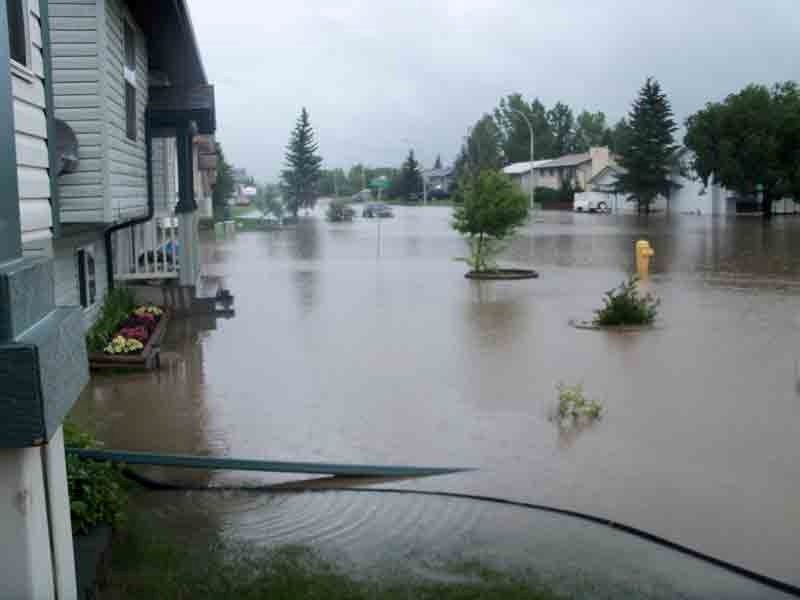 Water floods the intersection of Robinson Ave. and Lee St. in Penhold early on July 26. Over two inches of rain fell in less than two hours, overwhelming the town&#8217;s