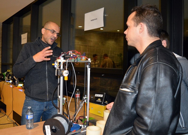 Darren Anderson, right, listens to Red Deer College mechanical engineering student Tareq Lafi as he explains a 3-D printer during the Family Literacy Festival at the