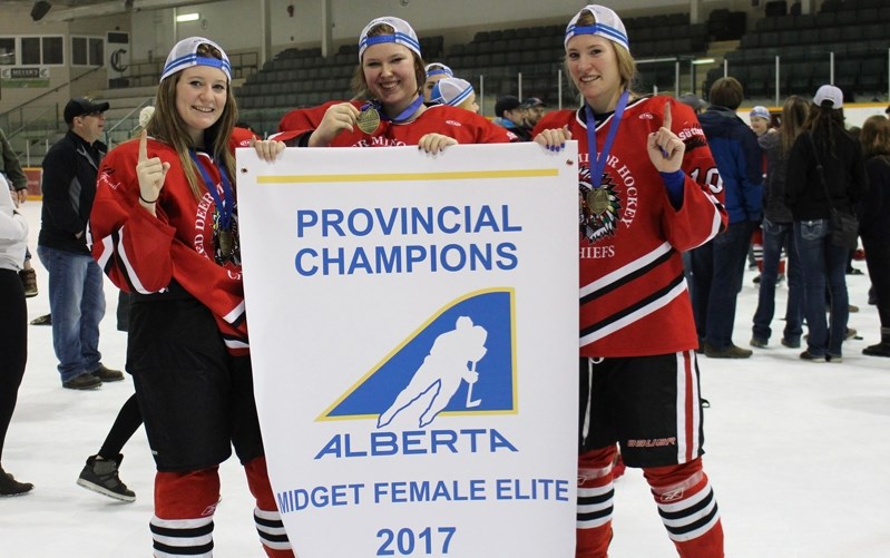 Innisfail hockey players, Samantha Thompson, left (defence), Jayda Thompson, centre (goaltender) and Makenna Doel, right (forward/defence), celebrate their gold medal at the