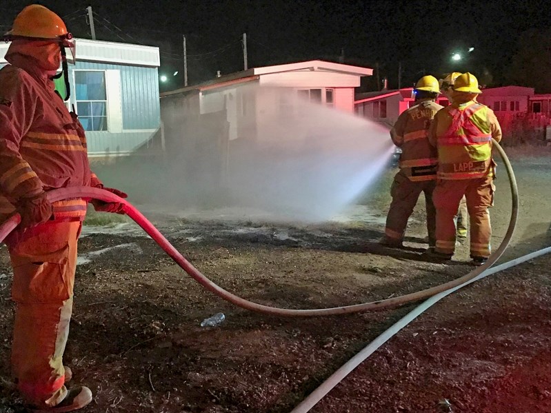 Penhold firefighters work to put out the small grass fire that was burning near homes at Penhold Estates on Saturday night (Sept 2). The firefighters were called to the