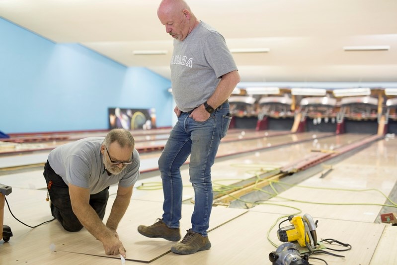 Gary Lazowski, left. and Nelson Joseph work on a new playing surface at the Innisfail Bowling Lanes on Sept. 27.