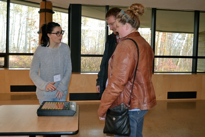 Innisfail election worker Kayla Whymark (left) shows citizens how to register votes on the electronic system used for the advance vote on Oct. 14 at the Innisfail