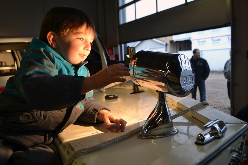 Daxton McQuaid is pleasantly fascinated with the head light on the Innisfail Fire Department&#8217;s rescue boat during the public barbecue on Oct. 11.