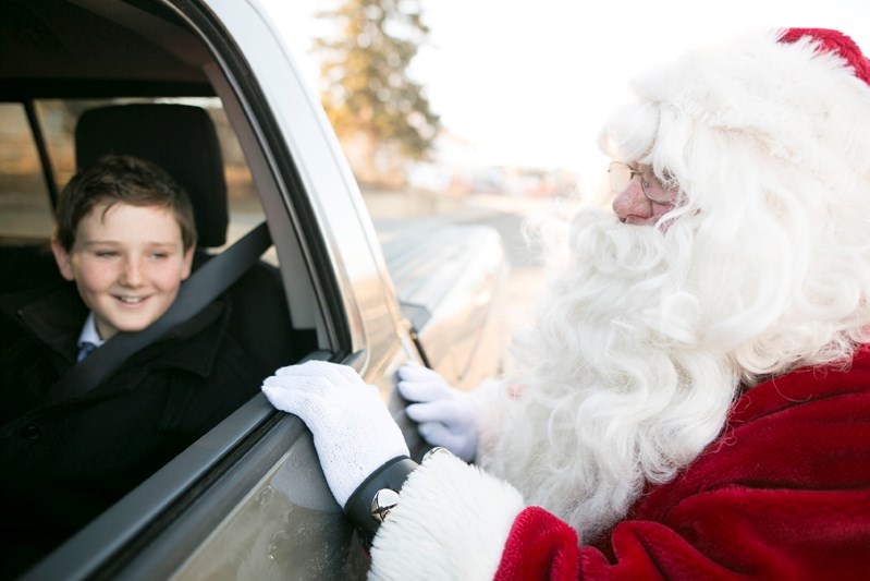 Santa Claus visits with a child in a passing vehicle during the Charity Check Stop event.