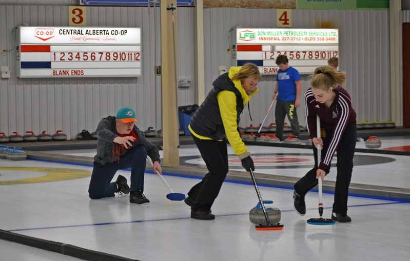 Curling coach Peggy Freeman, left, instructs members of the Innisfail High School curling team during a recent practice at the Innisfail Curling Club.