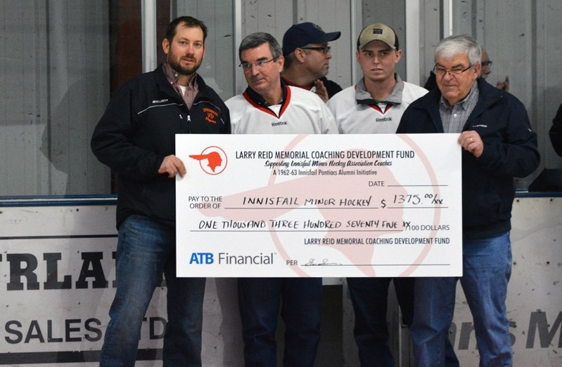 Members of the Larry Reid Memorial Coaching Development Fund present a cheque for $1, 375 to Randy Graham with Innisfail Minor Hockey, at left. Next to Graham is David Reid