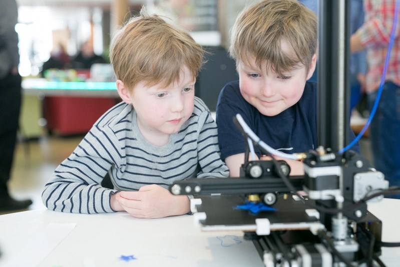 Will, left, and Sully Jenkins watch a 3D printer in action.