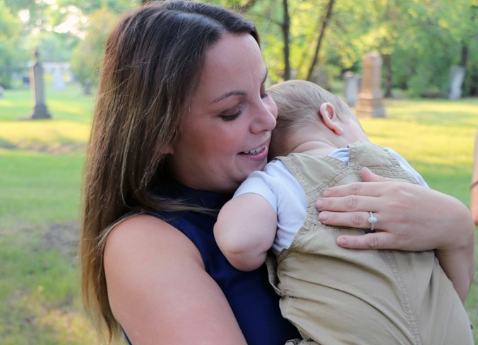  Nicole Lesko with her seven-month-old cousin Andrew at the Blessing of the Grave service in Winnipeg on July 20.