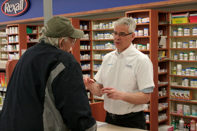 Local pharmacist Clark Jantzie discusses with a customer about the impacts lower generic drug prices will have on pharmacies as pharmacists across Alberta participated in a