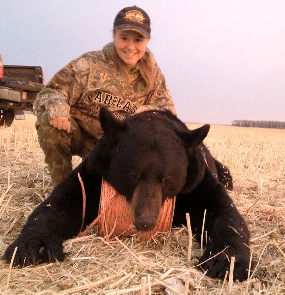 Madison Nimmo stands beside the bear that she shot while on a camping trip with her dad last September.