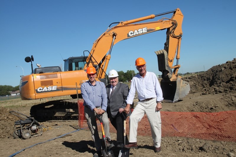 Bert Eggink (left), owner of Pearl Rose Construction, Penhold Mayor Dennis Cooper and owner of the new grocery store Jerry Knebel stand in front of the crane that has already 