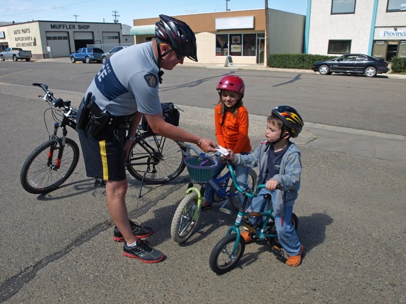 RCMP Const. Rick Buisseret gives six-year-old Henry Clark a ticket &#8211; a &quot;positive&quot; ticket for good cycling practices. Local RCMP are in partnership with the