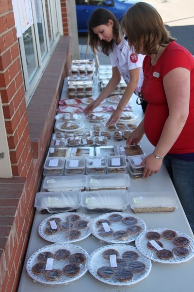 Amy Weleschuk and Stephanie Lessner, Scotiabank employees, lay out cakes, cookies and baked treats at the Scotiabank Bake Sale on Aug. 30 outside Scotiabank in Innisfail. The 