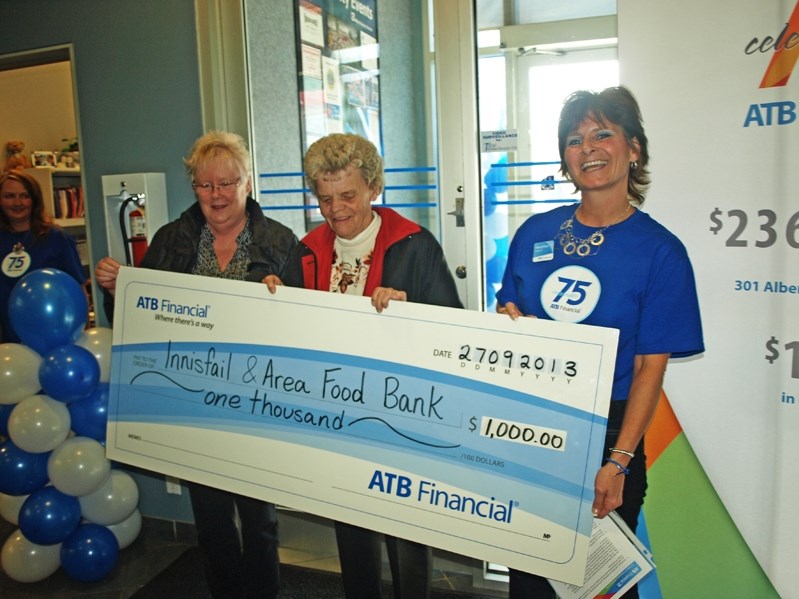 Heather Kirkham (right), ATB Financial branch manager in Innisfail, presents officials with the Innisfail Food Bank a cheque for $1,000 at the 75th birthday party for the