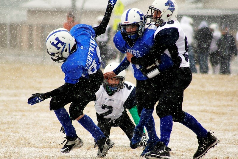 Cyclones players Reid Puttee, left, and Bret Marshall bring down a Hunting Hills blocker and ball carrier during last Saturday&#8217;s snowy championship game.