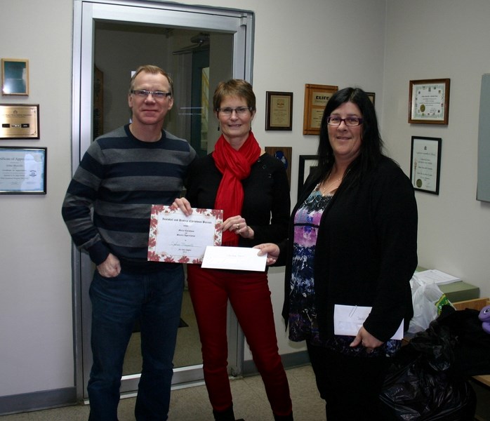 Johns Manville manager Jim Wilson (far left), and Cathy Ouellette, HR manager (far right), present Jane Duncalfe, Innisfail Christmas Bureau volunteer, with $8,000 raised by