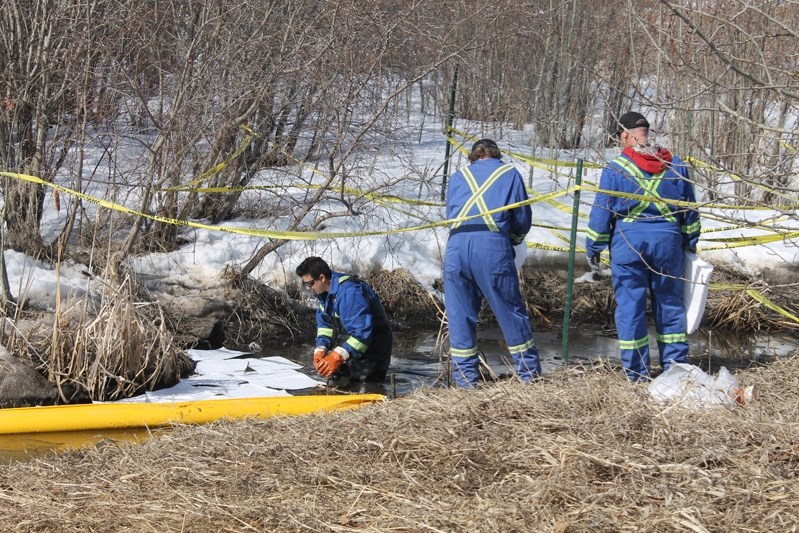 Innisfail town workers lay down absorbent pads onsite at the northeast corner of Dodd&#8217;s Lake where a hydrocarbon spill was reported on April 11.