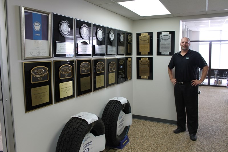 Jeff Denham, owner of Fourlane Ford, stands by his award wall which will soon include the 2013 President&#8217;s Award for excellence in customer satisfaction. His team has