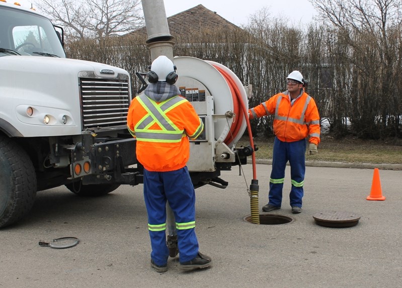 Town of Innisfail workers prepare equipment to vacuum debris from a sewer line on 56 Street on April 17 in order to allow a video inspection of the piping system.