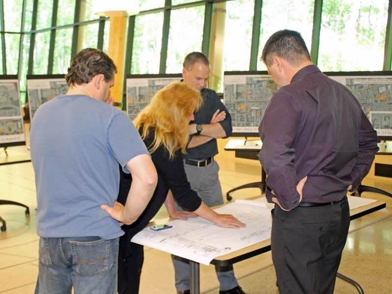 Two Innisfailians look at the engineering plans for Phase 3 of the downtown modernization project and Mat Reijnders (second from right) and Innisfail&#8217;s director of