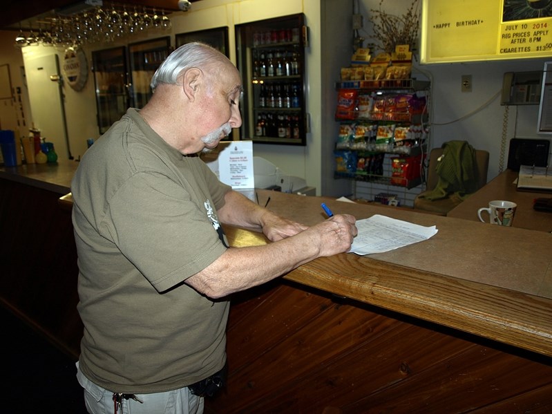 L.L. Behan signs the community-wide petition last week at the Royal Canadian Legion against the town&#8217;s plan to move the waste transfer site next to the Westwood trailer 