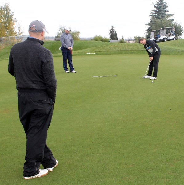 Craig Scott (left) and Simon Jones (second from left) watch as a fellow golf professional putts to the cup on Sept. 23.