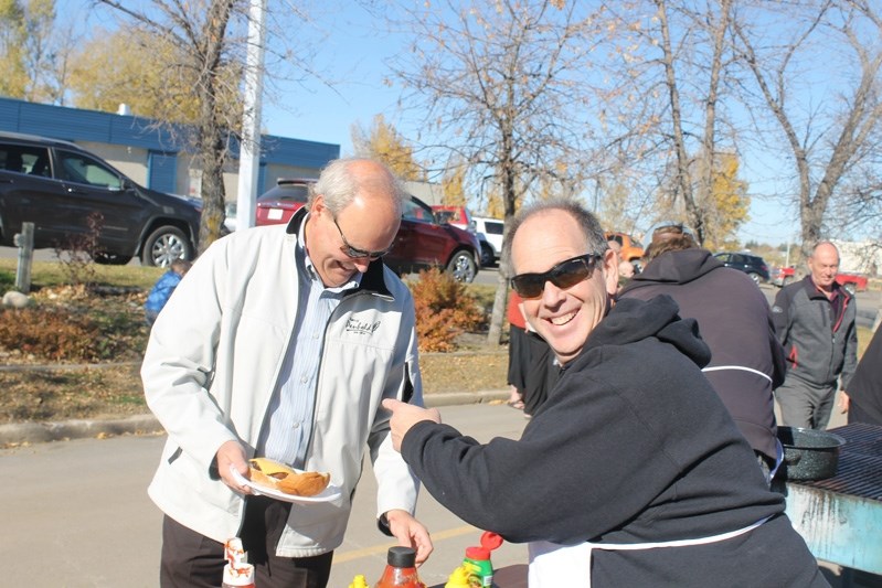 Innisfail Coun. Mark Kemball &#8216;busts&#8217; Rick Binnendyk, Town of Penhold chief administrative officer, during the barbecue celebrating the opening of Main Street on