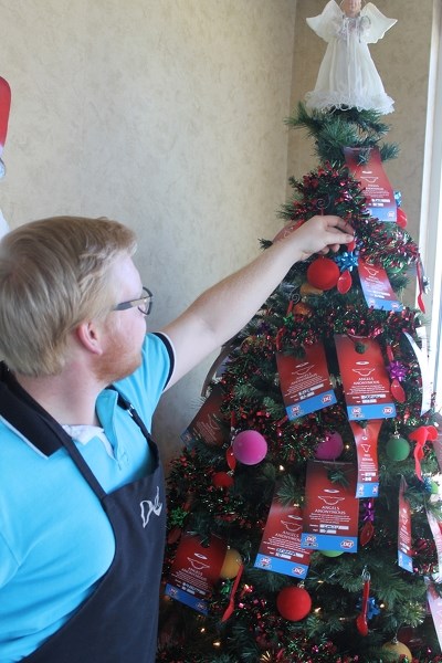 Brett Kemball puts a gift tag from Angels Anonymous on the Dairy Queen Tree.