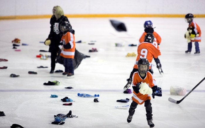 Volunteers collect items from the annual Stuffy, Toque, or Mitt Toss on Nov. 27 at the Innisfail Arena after the first goal was scored during the game between the Innisfail