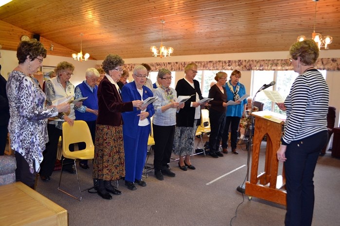 Evelyn Erickson, a representative from the Peace Lutheran Church, leads seniors at Autumn Glen Lodge during the opening of the service for World Day of Prayer, which was