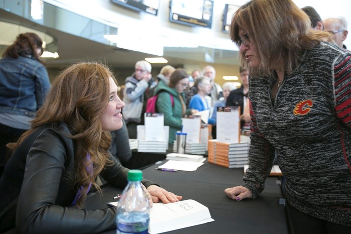 Clara Hughes, a multiple medal winner in both the summer and winter Olympic games, signs a copy of her book Open Heart, Open Mind for Maryse Beeney after giving a