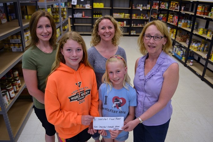 Brenda Hand, assistant coordinator at the Innisfail and District Food Bank (right), accepts a cheque of $260.40 from officials and young players of the Innisfail Female Atom