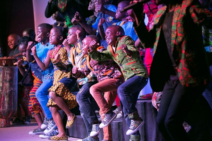 Members of the Watoto Children&#8217;s Choir, accompanied by a group of adults, dance together on stage at the Innisfail Alliance Church on April 23. The choir, which is on a 