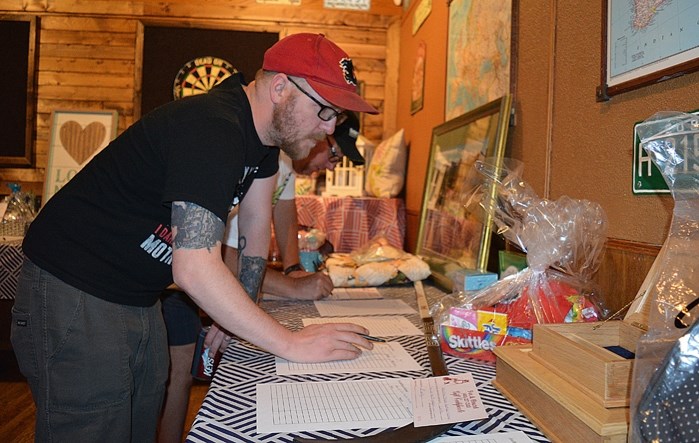 Matthew Garlund, front, and Gord Thompson look at donated items up for grabs during a silent auction at the Fox &#038; Hound and Mulligans on June 4. Money raised during the