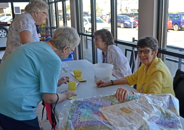 Members of the Innisfail Seniors Drop-In Centre &#8211; Jean Bennett (lower right) and Winona Raiwet (upper right) &#8211; recently sell tickets at the Co-op for a quilt