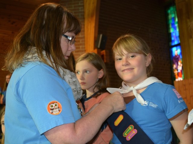 Brownie leader Joanne Schatz, left, placed a graduation badge on Eva Scott as she graduated from Brownies to Guides during the Girl Guides of Canada Golden Poplar