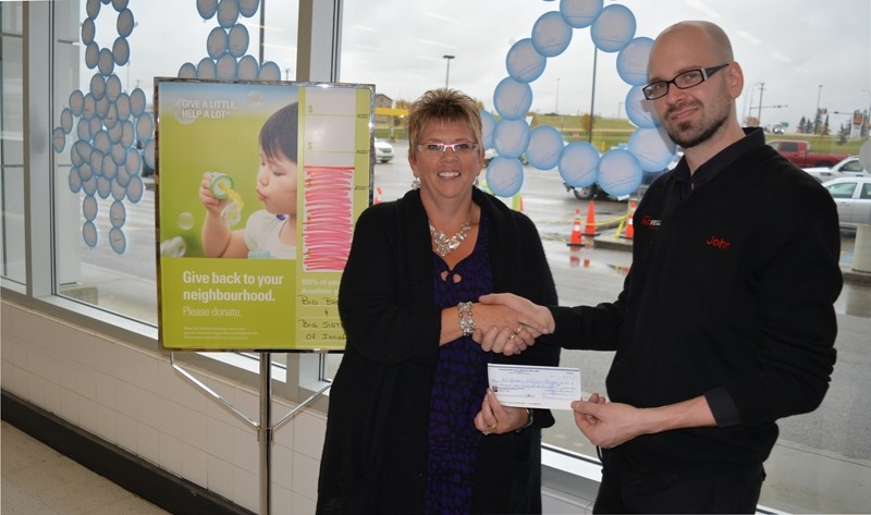 Sherry Dijkstra of Big Brothers Big Sisters of Prairies to Peaks, left, receives a cheque for $2,900 from John Harris, owner of John&#8217;s no frills after customers at his