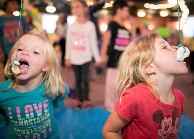 Cami Mix, left, and Phoenix Redmond bob for doughnuts during a carnival hosted by the Alliance Church on Sept. 22.