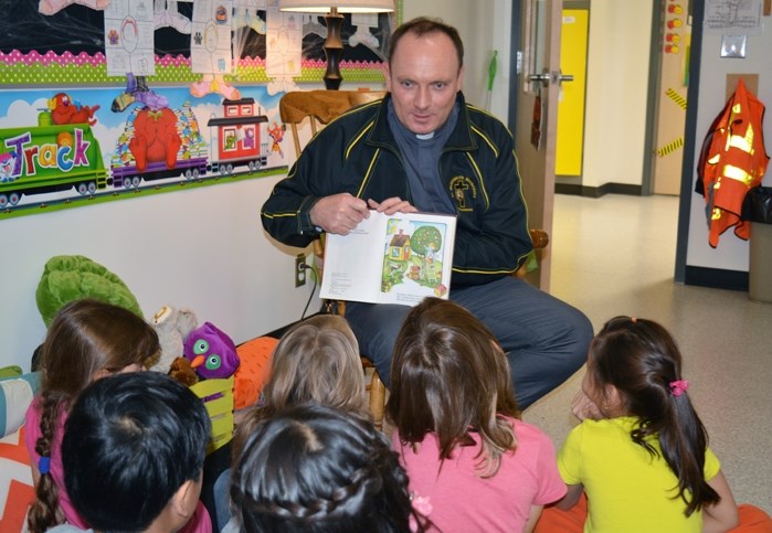 Father Tom Puslecki reads to grades 1 and 2 students at St. Marguerite Bourgeoys School in Innisfail. The local priest at Our Lady of Peace Catholic Church read to students