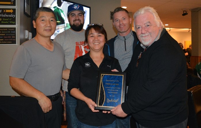 Penhold mayor Dennis Cooper, far right, presents a plaque to Kim Kim, centre, and her husband Robert, left, to commemorate the Penholder&#8217;s 75 years in business. Joining 