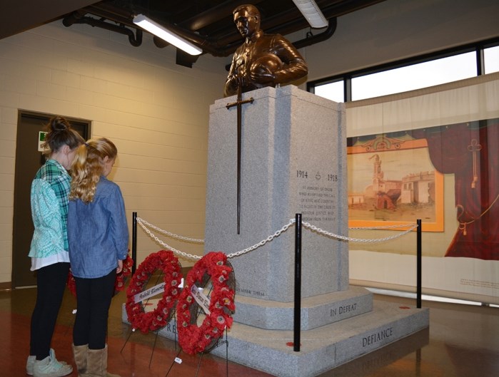 Harper Johnson, right and Lauren Bichel, both from Penhold Elementary School, lay a wreath at the cenotaph in Penhold during the taping of a special video for the