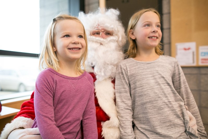 Cami, left, and Carly Mix pose for a photo with Santa Clause during his visit to the Innisfail Library/Learning Centre last Saturday for Innisfail&#8217;s Hometown Christmas.