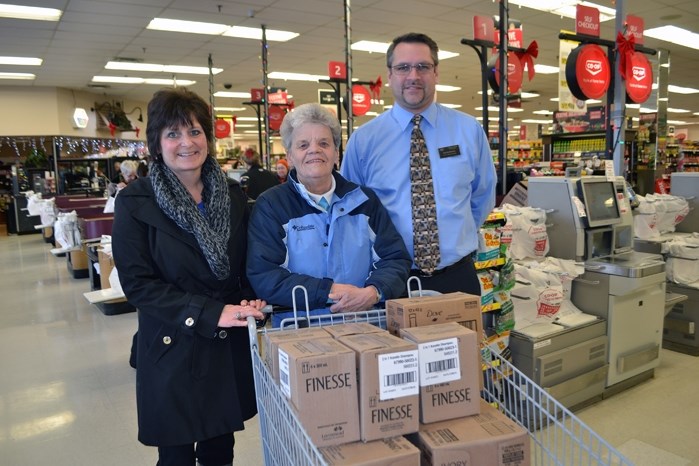 Heather Kirkham, president-elect for the Rotary Club of Innisfail, left, and Darren Andres, food centre manager at Co-op, hand over $500 worth of essential personal products