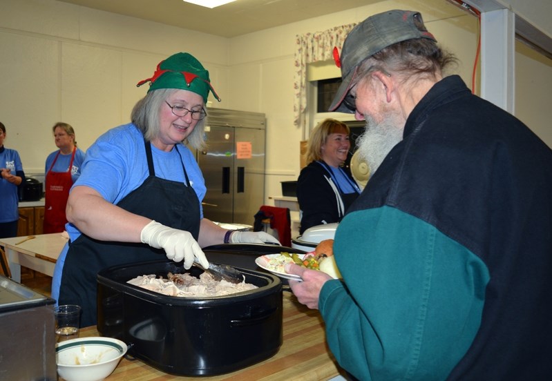 Johns Manville employee June Bush helps serve turkey during the company&#8217;s first Christmas turkey supper at Innisfail United Church on Dec. 19. The supper fed about 250