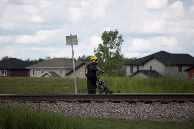  A child crosses railway tracks near the intersection of 52nd and 54th avenues on June 25.