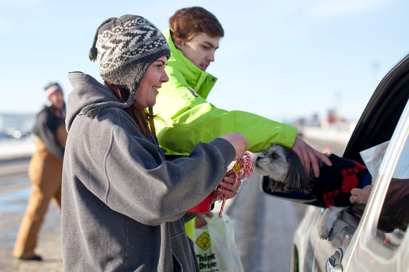 Michelle Hassard, left, and Olds Grizzlys player Sean Davies collect a donation from a motorist and his dog during the charity checkstop in Olds last Saturday.