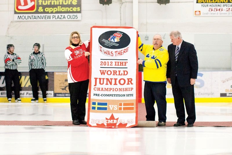 From left, Mayor Judy Dahl, Olds Grizzlys president Jim Ross and IIHF World Junior Championships 2012 executive director Al Coates unveil a host banner for the world junior