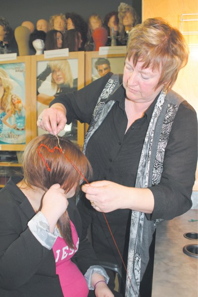 Instructor Lee Cenaiko threads a Valentine&#8217;s Day heart into Grade 11 student Sarah Jewkes hair during an orientation session for a new hairstylist trade pre-employment