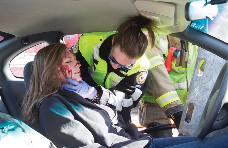 Emergency responders tend to an Olds High School student playing the victim of a car crash on May 1, 2013, as part of a P.A.R.T.Y. Program mock crash event to show Grade 10